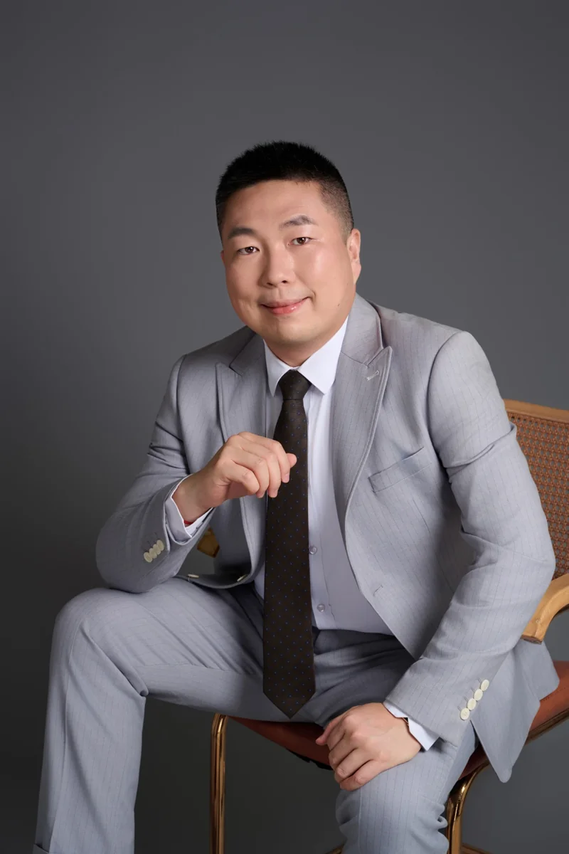 Lei Jin, REALTOR® with Pinnacle Real Estate Group, in a gray suit.